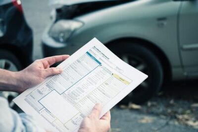 Man viewing insurance form at a car accident, wondering if a car accident lawyer will deal with insurance companies for me