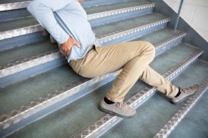 Man clutching his back after slipping down the stairs