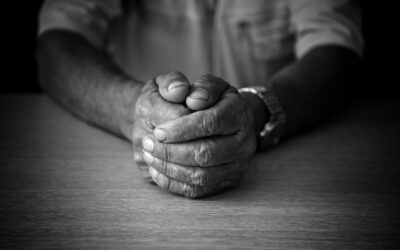 Elderly mans hands folded on table