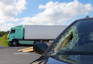 Aftermath of semi truck accident with shattered passenger vehicle windshield