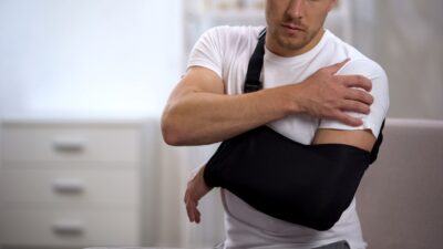 Injured man in sling feels hurt shoulder