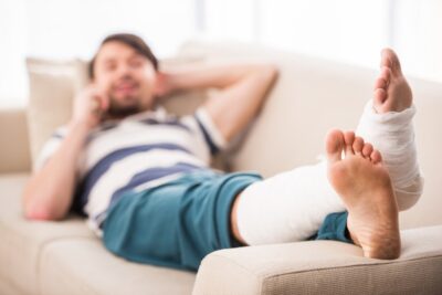 Man lying on a sofa in a cast