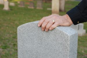 Man rests hand on loved ones gravestone