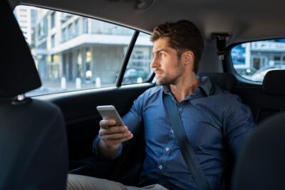 Man in back seat of car with phone