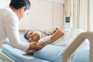 A woman visits her friend in the hospital. A visit can do wonders to brighten someone’s day after a car wreck.