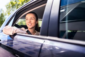 Woman in back seat of car with window rolled down