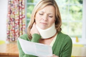 Woman in neck brace looks at paperwork