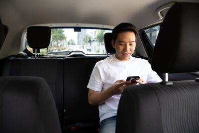 Asian man using smartphone in a lyft