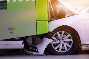 Compact car crushed under a bus