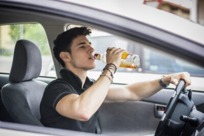 Teenage guy drinking behind the whee