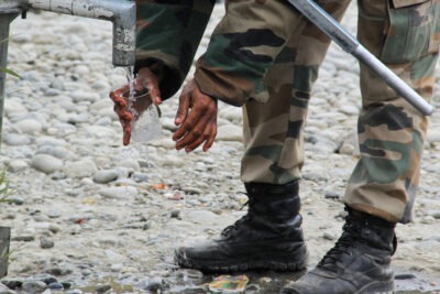 An armed forces member filling a glass with water