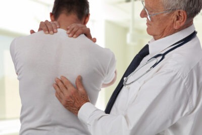 Doctor helping patient with back pain scaled