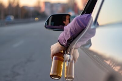 Guy holding bottle of beer out window scaled