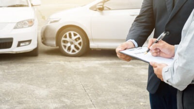 Insurance agent filling out accident paperwork scaled