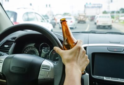 Person holding a beer bottle while driving