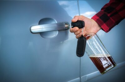 Man unlocking the car door with beer bottle in hand