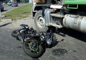 Crashed motorcycle next to oil truck