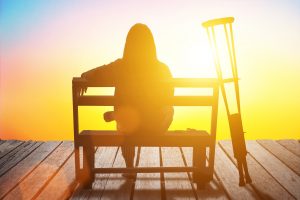 Woman with crutches watching the sunrise scaled