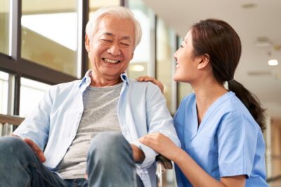 Asian man in wheelchair with caregiver