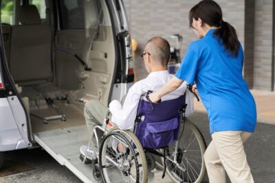 Caregiver loading man in a wheelchair on a van