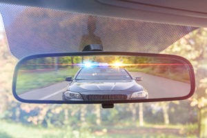 Cop approaching in the rearview mirror scaled