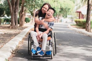 Woman hugging asian son in wheelchair