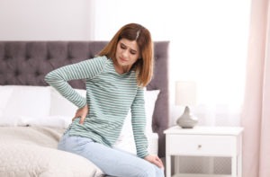 Woman in bed with back pain scaled