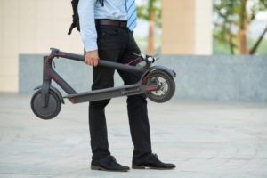 Businessman holding a folded electric scooter