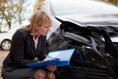 Female adjuster recording car accident damage