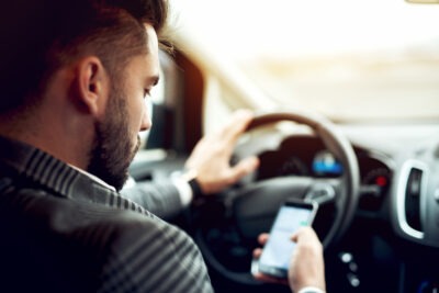 Man checking phone behind the wheel scaled