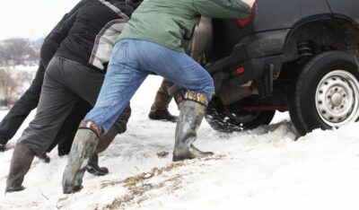 People pushing a car out of snow