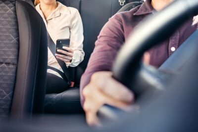 Woman checking phone in a rideshare car scaled