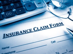 Close up on insurance claim form with calculator scaled