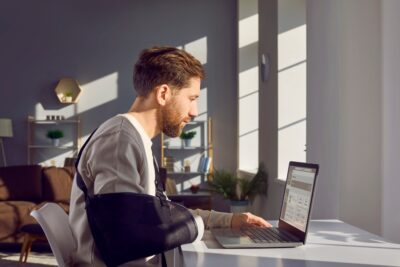 Man with broken arm filling out a claim form