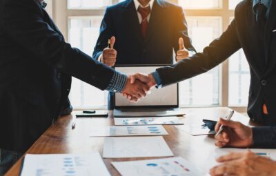 Two men shake hands before a mediator as the mediation process reaches a mutually beneficial resolution. An experienced personal injury lawyer can tell you more about what mediation is in a personal injury case.