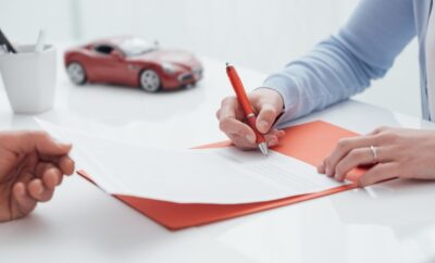 A person signing car insurance paperwork. A lawyer can explain if a closed car insurance claim can be reopened.