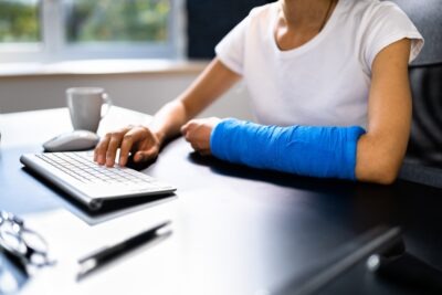 Woman in cast at desk