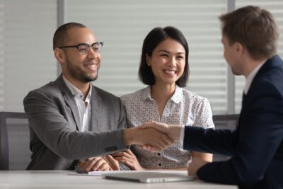 A male attorney shaking hands with a young couple