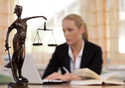 Female lawyer working next to scales of justice scaled