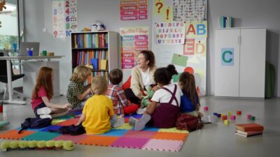 Teacher sitting on the floor with her students