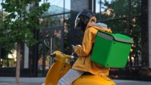 A food delivery driver in a yellow jacket on a motorized scooter ponders if they need a lawyer after a food delivery accident claim.