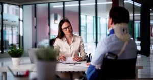 An attorney speaking to their client who has suffered a neck injury at work and discussing a Georgia workers’ compensation settlement chart.