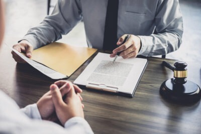 Lawyer sits at a desk with client and explains how to keep identity private during a sexual assault case.