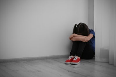 A sad child. Learn how to report a sports coach or athletic trainer for sexual abuse.