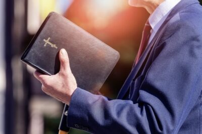 A pastor holds a bible and wonders if clergy are mandated reporters in Georgia.